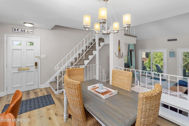 dining space with wood finished floors, stairway, a chandelier, and baseboards