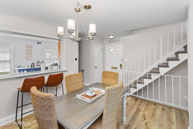 dining area featuring a chandelier, stairway, and light wood-type flooring