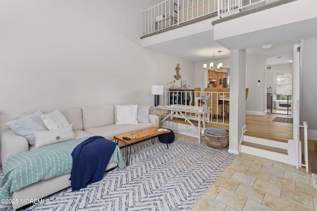 living room featuring a chandelier, baseboards, stone finish flooring, and a towering ceiling