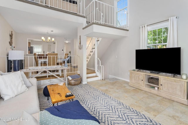 living room featuring stairway, a chandelier, a high ceiling, and baseboards