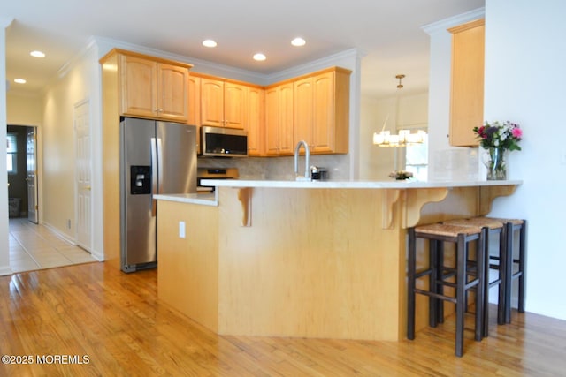 630 Springfield Ave, Pine Beach, NJ 08741 - kitchen with appliances with stainless steel finishes, ornamental molding, a breakfast bar area, light wood-type flooring, and tasteful backsplash