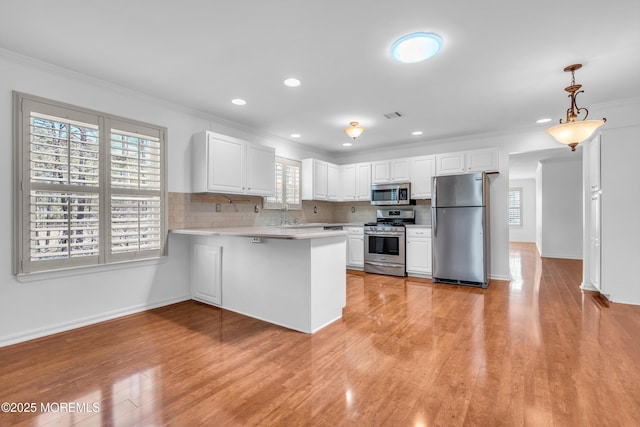 235 Prince Charles Ct, Toms River, NJ 08757 - kitchen with appliances with stainless steel finishes, light countertops, crown molding, a peninsula, and white cabinetry