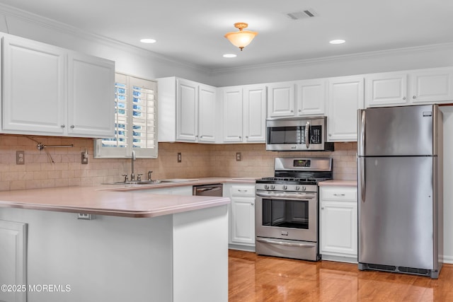 235 Prince Charles Ct, Toms River, NJ 08757 - kitchen with appliances with stainless steel finishes, a peninsula, light countertops, a sink, and white cabinetry