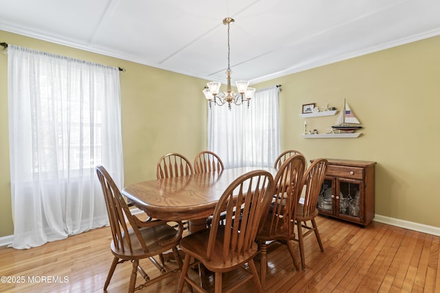 dining area featuring a chandelier, light wood-type flooring, baseboards, and crown molding