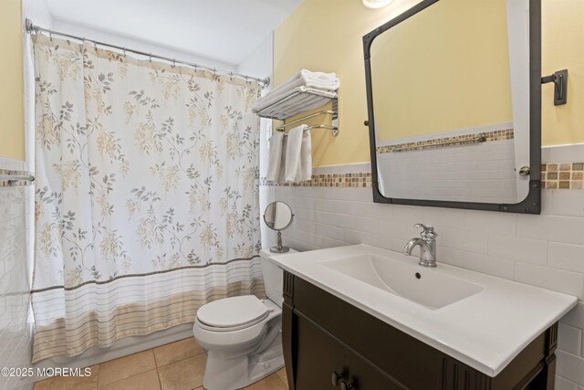 full bathroom featuring tile walls, toilet, vanity, a wainscoted wall, and tile patterned floors