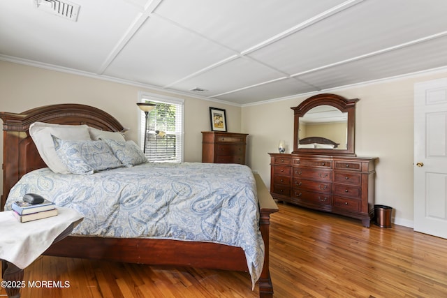 bedroom featuring wood finished floors, ornamental molding, and baseboards