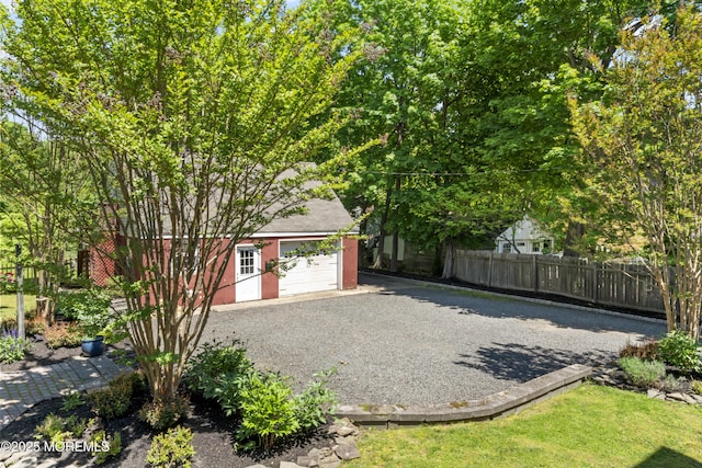 exterior space with fence, driveway, and an outdoor structure