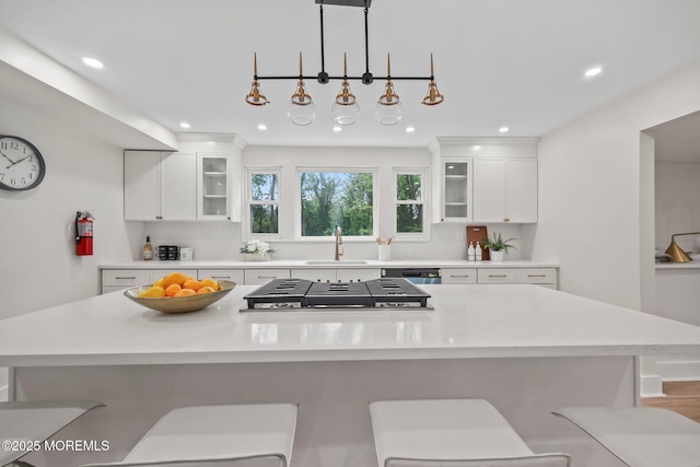 kitchen featuring backsplash, a sink, a center island, light countertops, and recessed lighting