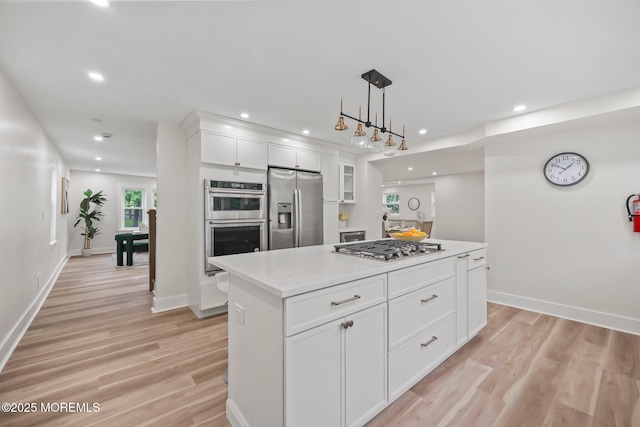 kitchen with stainless steel appliances, white cabinets, a kitchen island, light wood-style flooring, and recessed lighting