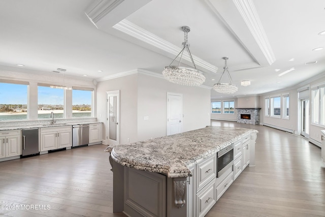 kitchen featuring stainless steel appliances, baseboard heating, a chandelier, a sink, and ornamental molding
