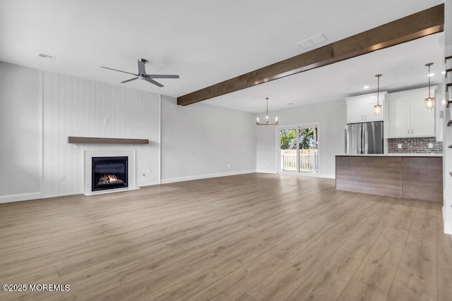 7 Leifried Ln, Tuckerton, NJ 08087 - unfurnished living room featuring light wood-type flooring, a ceiling fan, a lit fireplace, a chandelier, and beam ceiling