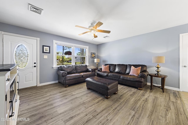 living area with a ceiling fan, light wood finished floors, and baseboards