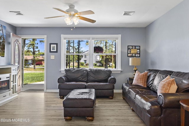 living room featuring wood finished floors, baseboards, plenty of natural light, and ceiling fan