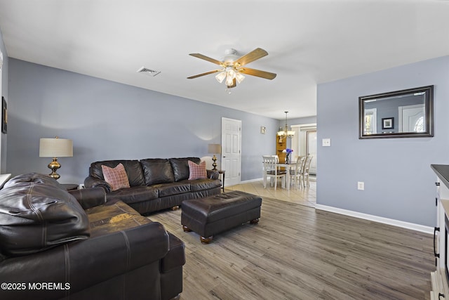 living area with ceiling fan, light wood-style floors, baseboards, and a chandelier
