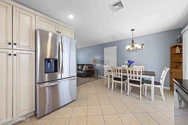 kitchen with stainless steel fridge with ice dispenser, cream cabinetry, light tile patterned flooring, a chandelier, and dark countertops