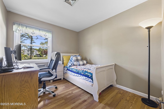 bedroom featuring wood finished floors, an office area, and baseboards