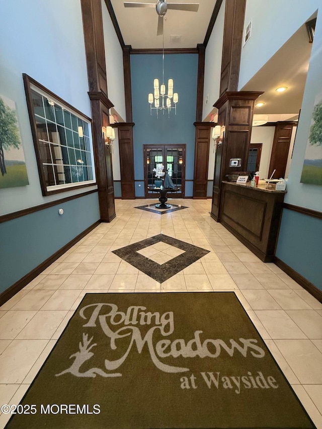 welcome area with a towering ceiling, a chandelier, ornate columns, ornamental molding, and a ceiling fan