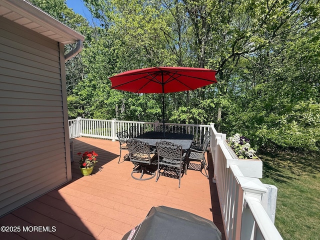 deck featuring outdoor dining area and view of wooded area