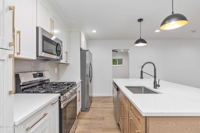 kitchen with stainless steel appliances, a sink, light wood-type flooring, an island with sink, and tasteful backsplash