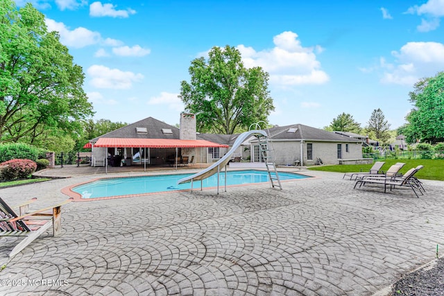 view of pool featuring fence, a water slide, and a patio area