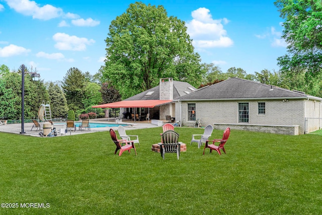 rear view of house with an outdoor pool, a patio, a lawn, and brick siding
