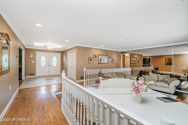 living area featuring ornamental molding, recessed lighting, baseboards, light wood finished floors, and a skylight