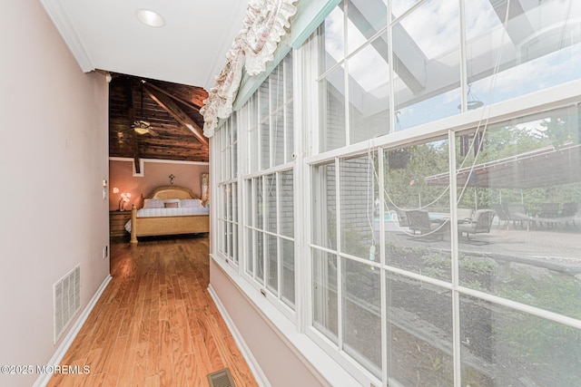 hall featuring wood finished floors, baseboards, a high ceiling, and beamed ceiling