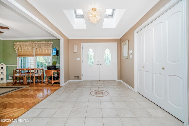 entryway featuring a skylight, ornamental molding, and baseboards