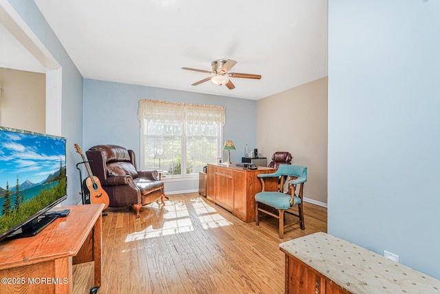 office area with a ceiling fan, light wood-style flooring, and baseboards