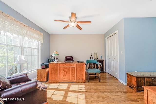 home office with a ceiling fan, light wood-type flooring, and baseboards