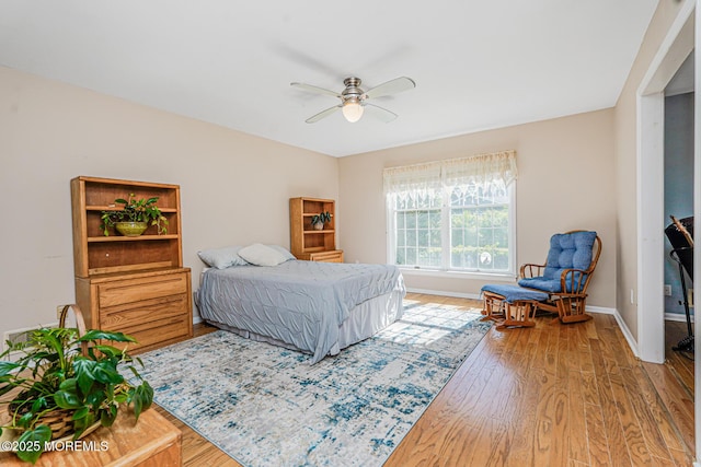 bedroom with light wood finished floors, baseboards, and ceiling fan