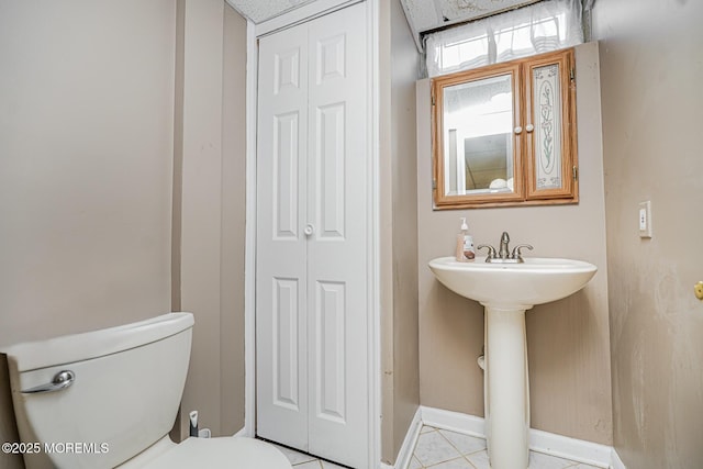 bathroom featuring toilet, baseboards, and tile patterned flooring