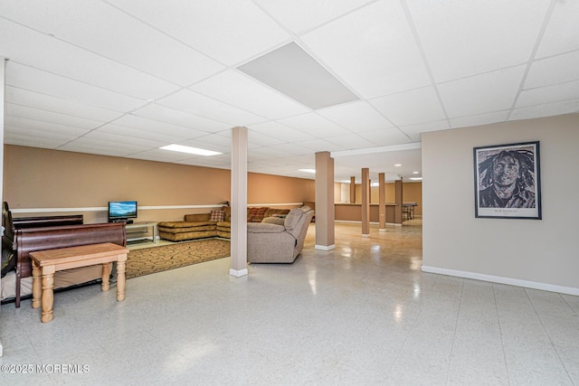 living area with a drop ceiling and baseboards