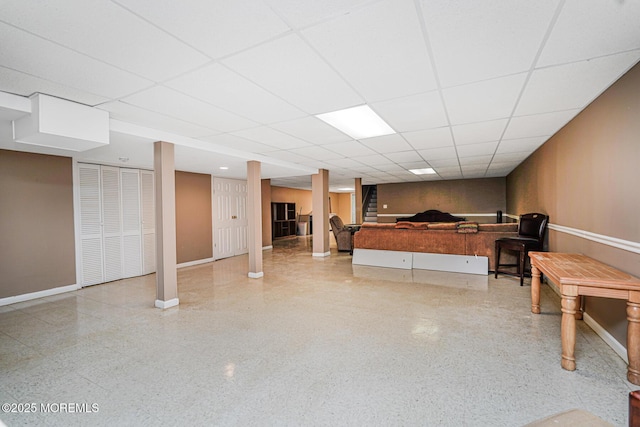 finished basement with a paneled ceiling and baseboards