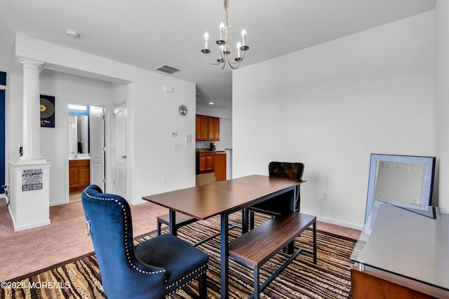 dining room featuring decorative columns, a chandelier, light colored carpet, and baseboards