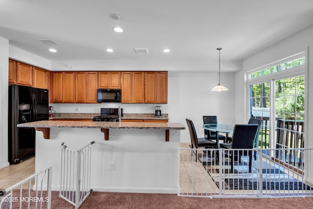 kitchen with black appliances, light stone countertops, recessed lighting, brown cabinetry, and a kitchen breakfast bar
