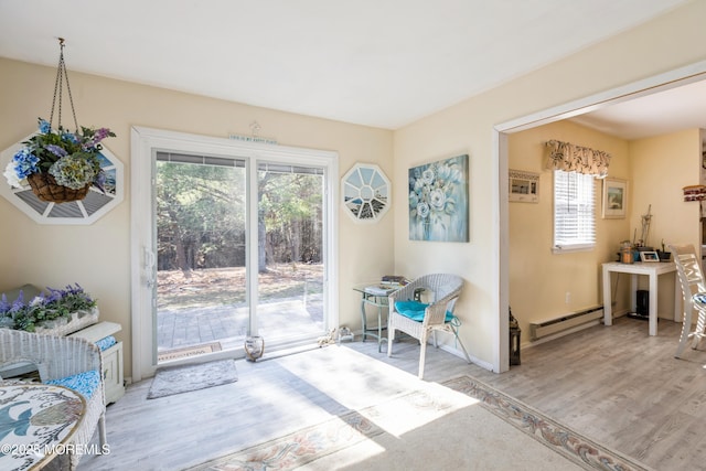 dining area featuring light wood finished floors, a baseboard radiator, and baseboards