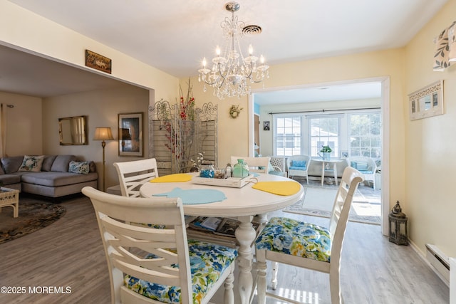 dining area featuring a baseboard radiator, wood finished floors, and a chandelier