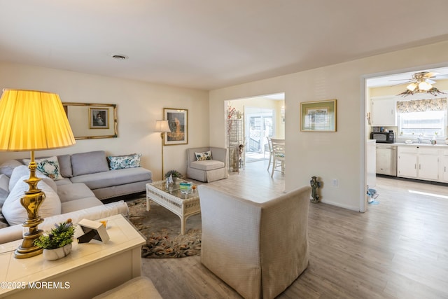 living area featuring light wood finished floors and ceiling fan