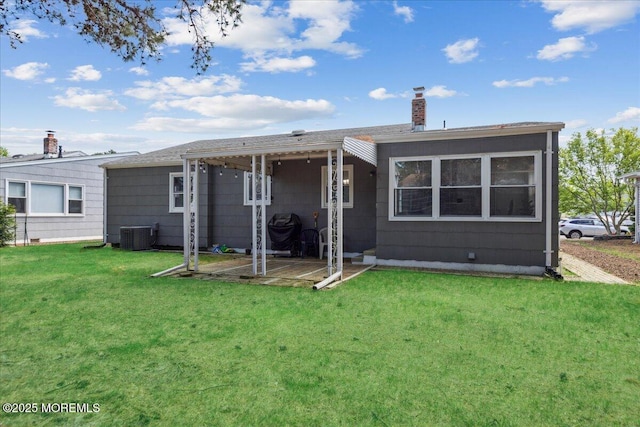 rear view of house featuring a chimney, a lawn, and central AC