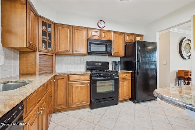 kitchen featuring black appliances, brown cabinets, light stone countertops, and backsplash
