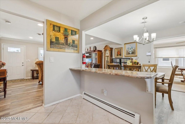 kitchen featuring a baseboard radiator, a chandelier, a kitchen breakfast bar, healthy amount of natural light, and crown molding
