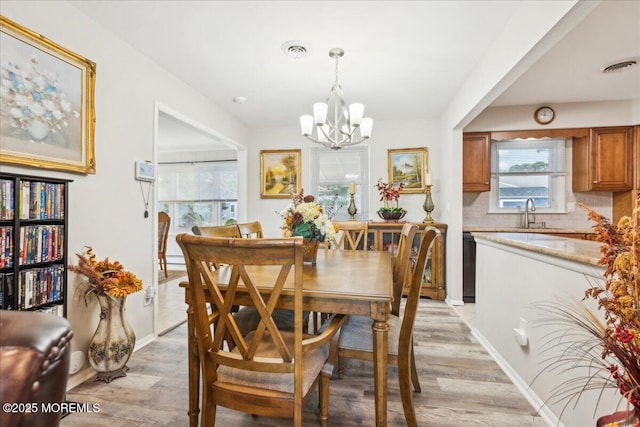dining area with a chandelier, light wood-style floors, and baseboards