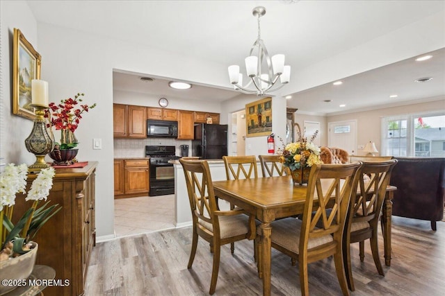 dining room with a chandelier, light wood finished floors, and recessed lighting