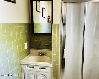 bathroom with tile walls, vanity, and an enclosed shower