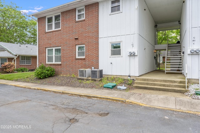 41D Cambridge Ct, Lakewood, NJ 08701 - rear view of house with brick siding, stairs, board and batten siding, and central AC unit
