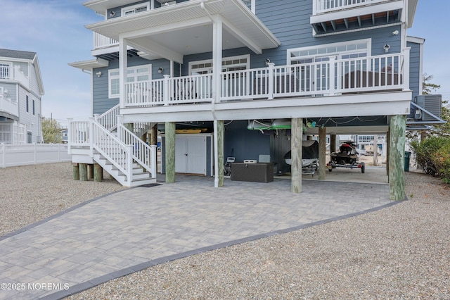 back of house featuring a carport, cooling unit, stairs, and decorative driveway
