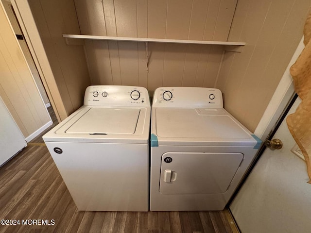 washroom featuring washer and dryer, dark wood-style flooring, and wood walls