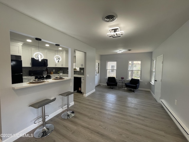 4B Greenwood Ln, Whiting, NJ 08759 - kitchen with black appliances, a baseboard heating unit, a kitchen breakfast bar, white cabinets, and backsplash