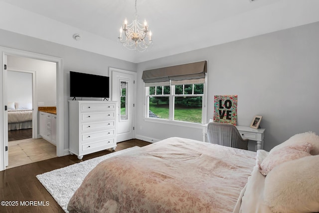 bedroom featuring a chandelier, wood finished floors, ensuite bath, and baseboards